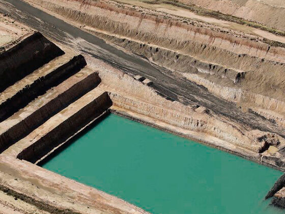 An open-cut mine pit cut in benches, with water pooled in the floor.
