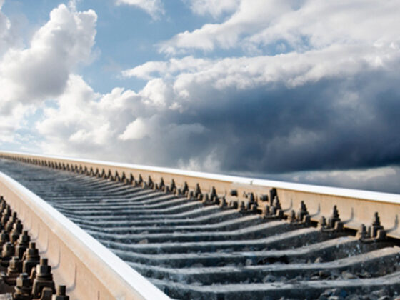 A railway line curving away under a wide, heavily clouded sky.